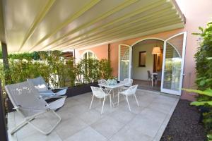 a patio with chairs and a table and a table and chairs at Appartamento EDEN - Clima, spazio esterno privato e parcheggio coperto in Marina di Campo
