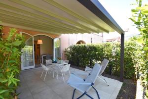 a patio with white chairs and a table at Appartamento EDEN - Clima, spazio esterno privato e parcheggio coperto in Marina di Campo