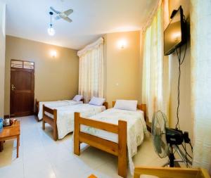 a room with two beds and a tv in it at Mama Thea homes in Moshi