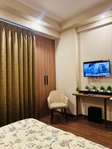 a bedroom with a bed and a desk and a tv at Apex Hub in Greater Noida