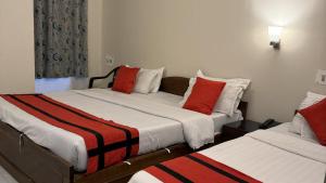 a bedroom with two beds with red and white pillows at HOTEL BREEZE NEW JALPAIGURI in Siliguri