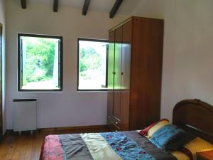 a bedroom with a bed and a dresser and two windows at Cuetu del Pradón in Piñeres