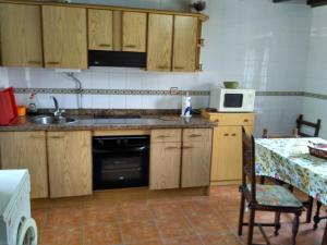 a kitchen with wooden cabinets and a table with a microwave at Cuetu del Pradón in Piñeres