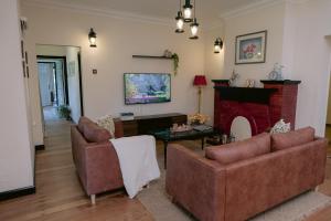 a living room with two couches and a fireplace at Rasah Golfers Cottage in Tanah Rata