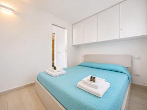 a bedroom with a blue bed with towels on it at Renew Terrace F with Swimming Pool 70m from the Beach in Baja Sardinia