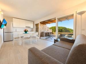 a living room with a couch and a table and a kitchen at Renew Terrace F with Swimming Pool 70m from the Beach in Baja Sardinia