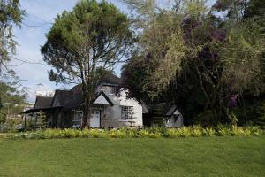 a white house with trees and a green lawn at Rasah Golfers Cottage in Tanah Rata