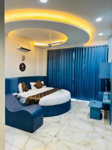a bedroom with two beds and a blue couch at Hotel JD Fortune in Anand