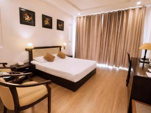 a bedroom with a bed and a table and a chair at Chau Pho Hotel in Chau Doc