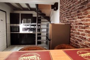 a kitchen with a wooden table and a brick wall at Chez Louis - Central Triplex in Rethel