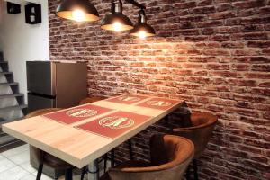 a table and chairs in a kitchen with a brick wall at Chez Louis - Central Triplex in Rethel