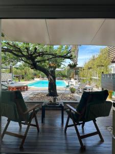 a patio with two chairs and a tree and a pool at The Bamboo villa in Casale la Cogna