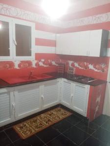 a kitchen with white cabinets and a red and white wall at Mon cœur Gris-Or in Rejiche