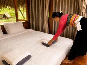 a woman is making a bed in a room at Mai Chau Ecohouse in Mai Châu +6 photos
