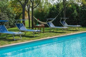 three chairs and a hammock next to a pool at Agriturismo Bandinelli in Castiglione della Pescaia