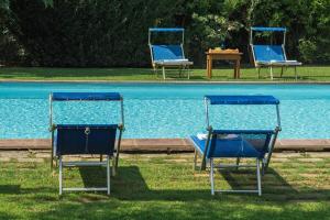three blue chairs sitting next to a swimming pool at Agriturismo Bandinelli in Castiglione della Pescaia