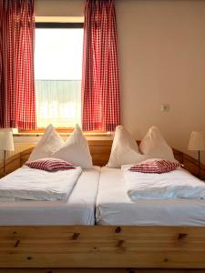 two beds in a room with a window with red curtains at Gasthof Fersterer in Lamprechtshausen