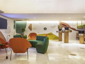 a living room with a green couch and orange chairs at Mercure Rio Boutique Hotel Copacabana in Rio de Janeiro