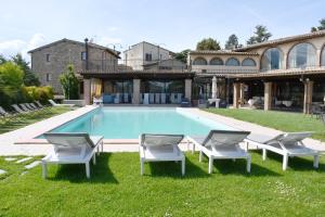 a swimming pool with chairs and a house at Grand Relais Laurenti in Gualdo Cattaneo