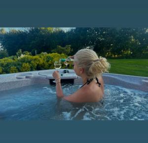 a woman in a hot tub with a glass of wine at Holmens Guesthouse in Lemming