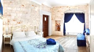 a bedroom with a bed and a stone wall at Ape Rossa in Castellana Grotte +39 photos