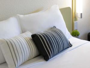 a white bed with a black and white pillow at ibis Budget Brisbane Airport in Brisbane +44 photos