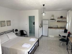 a bedroom with a white bed and a kitchen at Kambi rooms in Himare +13 photos