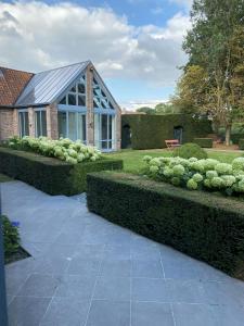 a garden with bushes and a house with a roof at Maison l'amitié in Ellezelles