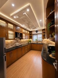 a large kitchen with wooden cabinets and a black counter top at Grand Residency Guest House in Islamabad