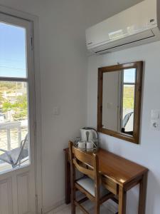 a dining room table with a mirror and a chair at Nikos Apartments in Lefkos Karpathou