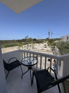 a balcony with a table and chairs and the beach at Nikos Apartments in Lefkos Karpathou