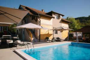 a swimming pool with chairs and umbrellas next to a house at Apartmani Dejavu na Drini in Ljubovija
