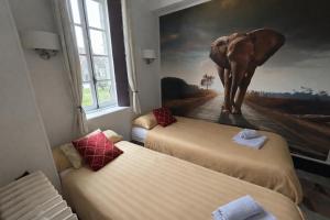 two beds in a room with an elephant painting on the wall at Chambre d'hôtes - demeure historique in Chantenay-Saint-Imbert