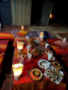 a table with plates of food on a red table cloth at Moon Dunes camp in Adrouine +15 photos