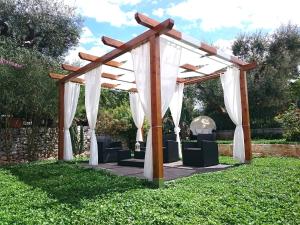 a wooden pergola with chairs under it in a yard at Ape Rossa in Castellana Grotte