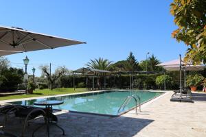a swimming pool with a table and an umbrella at Hotel Ristorante la Luna in Sarzana