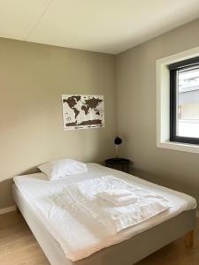 a white bed in a bedroom with a window at Oppheimhamna 10c in Bø