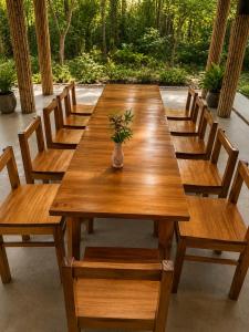 a long wooden table with chairs and a vase of flowers at Mai Chau Ecohouse in Mai Châu