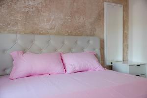 a pink bed with a white headboard and pink pillows at Apartmani Dejavu na Drini in Ljubovija