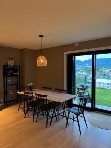 a dining room with a table and chairs and a large window at Oppheimhamna 10c in Bø