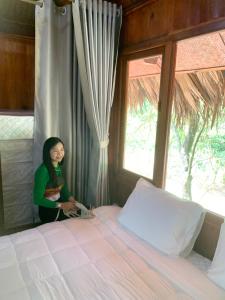 a woman standing next to a bed in a bedroom at Mai Chau Ecohouse in Mai Châu