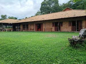 an old building with a grass field in front of it at Sítio dos Nogueira in Pará de Minas