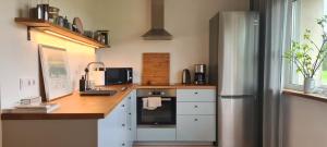 a kitchen with white cabinets and a stainless steel refrigerator at Cozy Home in Suuremõisa in Suuremõisa