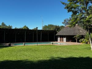 a swimming pool and a hut with a grass yard at Spacious Family Villa, close to Krugerpark entrance in Phalaborwa