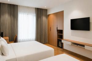 a hotel room with a bed and a flat screen tv at Adora Hotel Khe Sanh in Khe Sanh