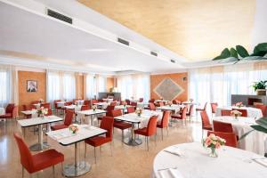 a restaurant with white tables and red chairs at Best Western Cavalieri Della Corona in Cardano al Campo
