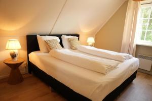 a bedroom with a bed with white sheets and pillows at Het Roodborstje 4-persoons in Lievelde