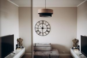 a room with a clock on the wall and a chair at Apartament Złote Noce in Augustów