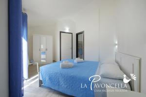 a bedroom with a blue bed with two pillows on it at Case Vacanze La Pavoncella in Teulada