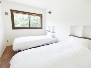two beds in a white room with a window at Locanda Furanora in Furano